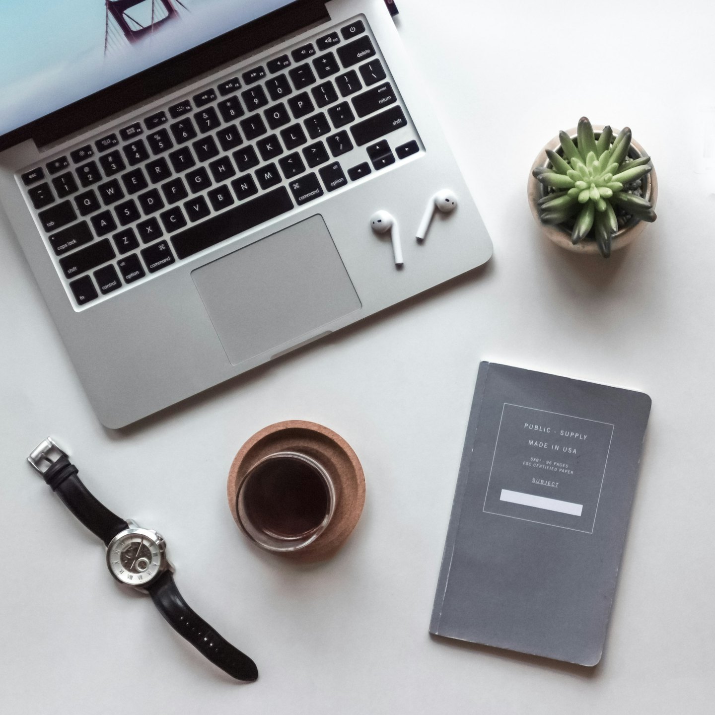 Laptop, notebook, and office supplies arranged on a white desk.